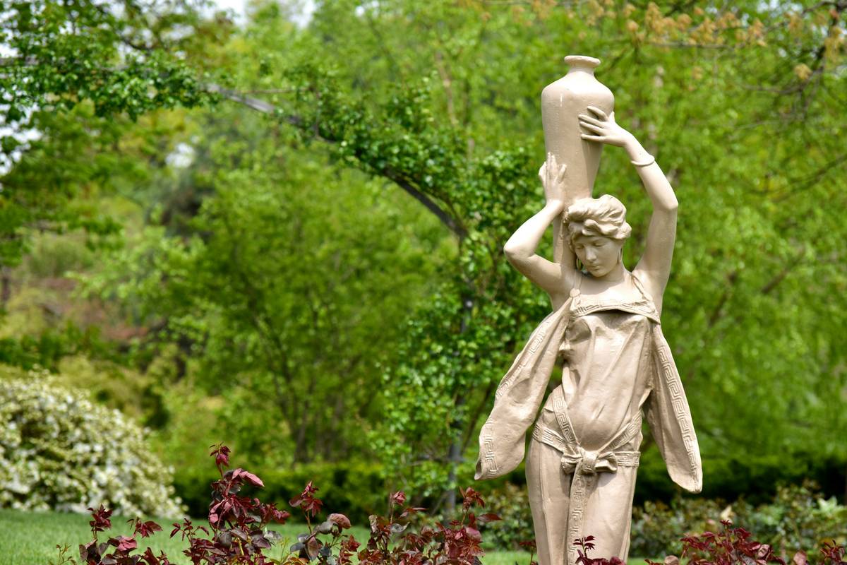 Infographic showing common garden statue damage types by material: spalling in stone, rust in iron, UV fading in resin, and stable patina in bronze.