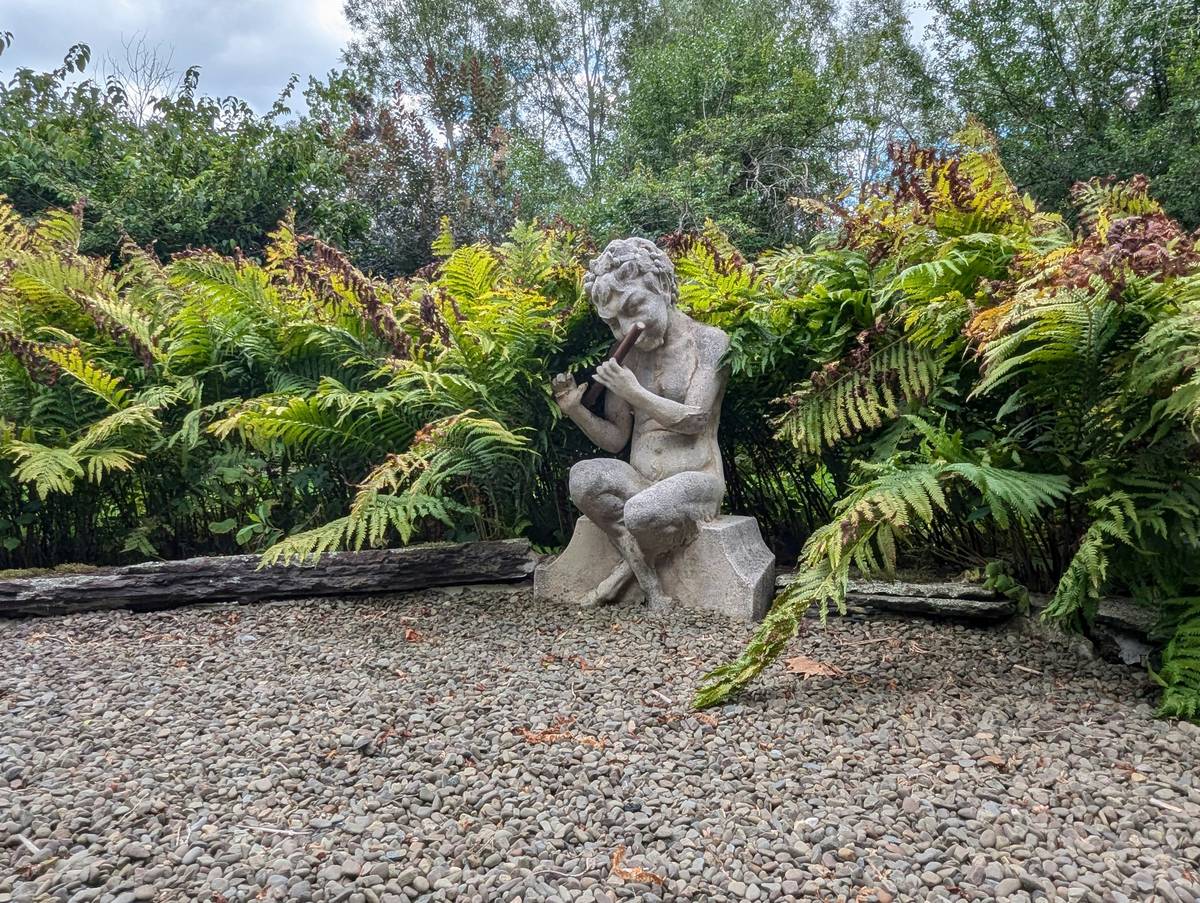 Classic stone cherub as outdoor garden centerpiece ideas with proper elevation on slate base